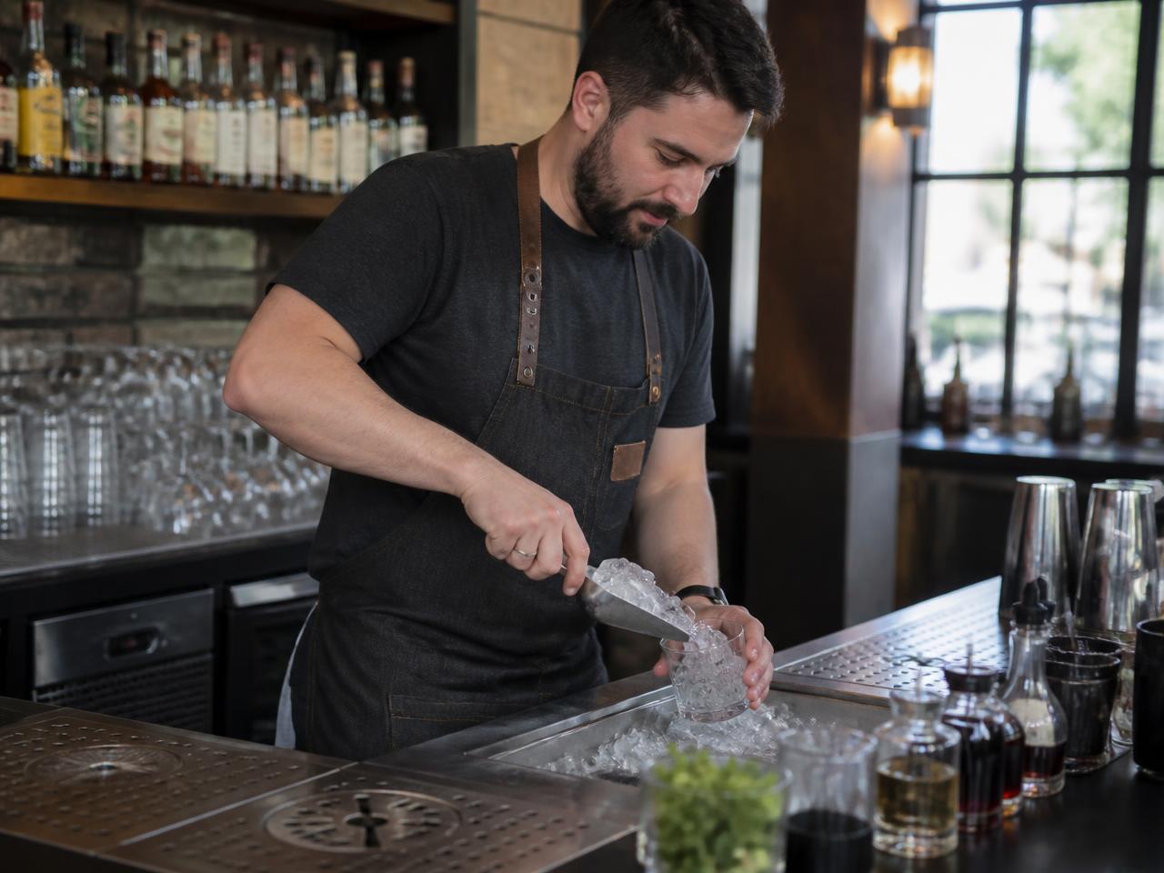 Bartender scooping clear ice in a busy restaurant bar